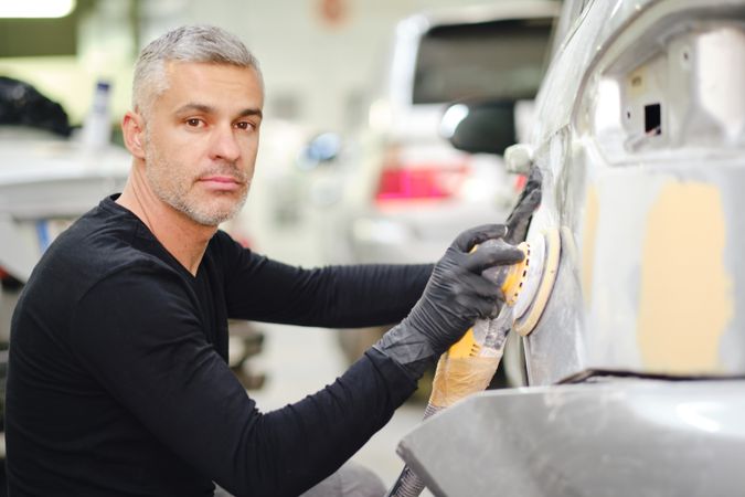Mechanic grinding paint from car detail