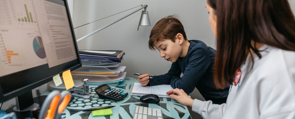 Mother helping her son with his homework while teleworking