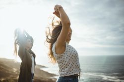 Happy female travelers enjoying freedom at seaside