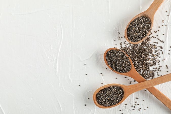 Wooden spoons and chia on neutral background, top view