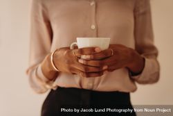 Close up of the hands of a Black woman in blouse holding a mug 4ZpWA0