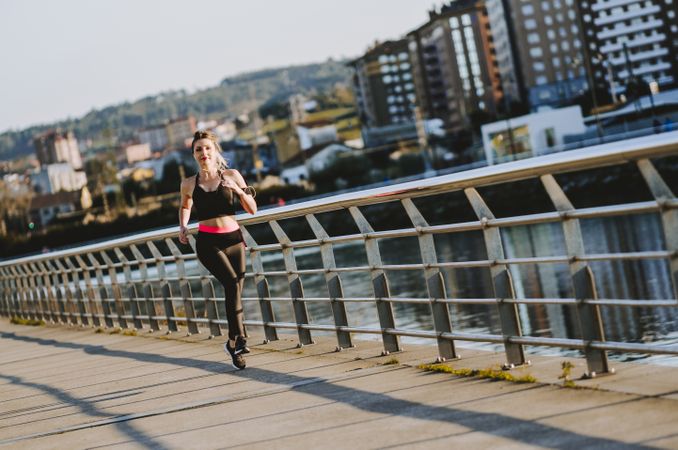 Woman running on embankment near water