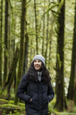 Happy young woman in the woods looking up