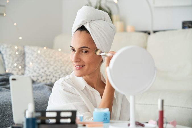 Content woman applying makeup and recording blog