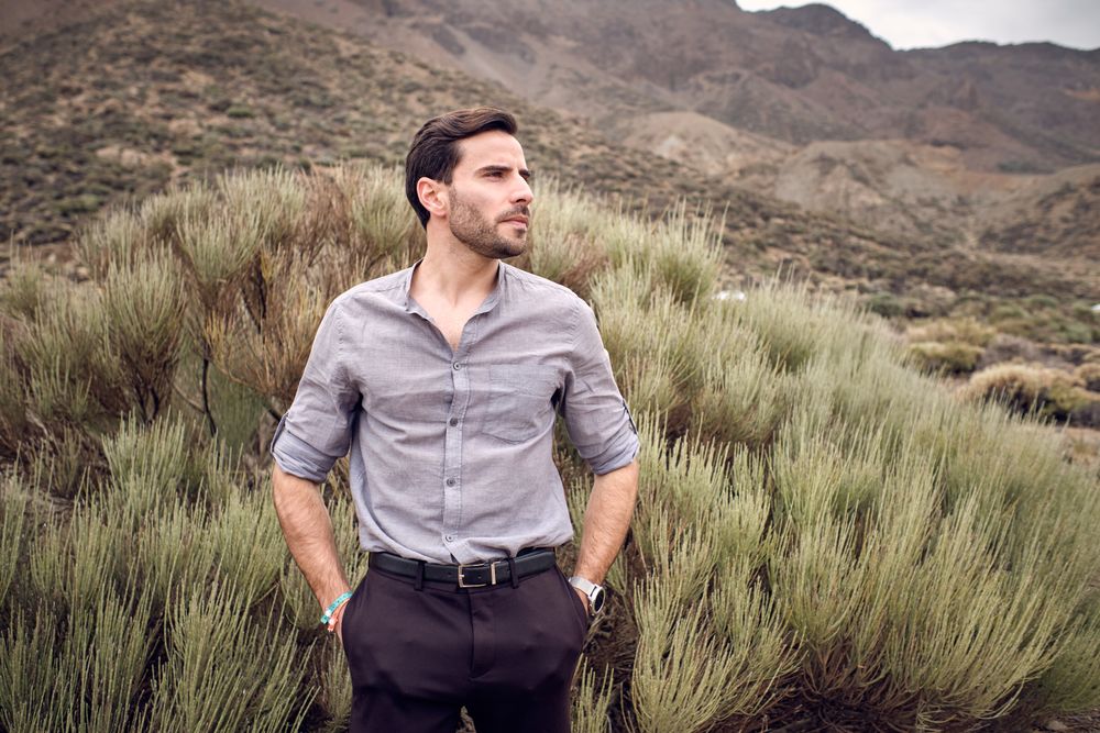Confident man standing in valley covered with savanna grass
