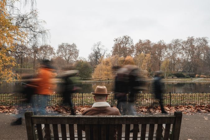 Anonymous man resting on bench near pond