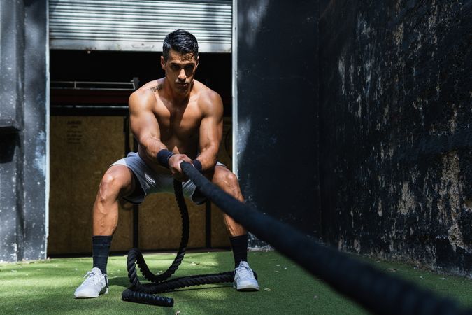 Muscular Hispanic sportsman pulling weight sled