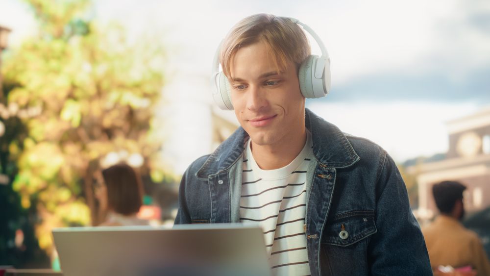 Stylish Student Working on Laptop Computer on a College Assignment Outdoors on a Terrace.