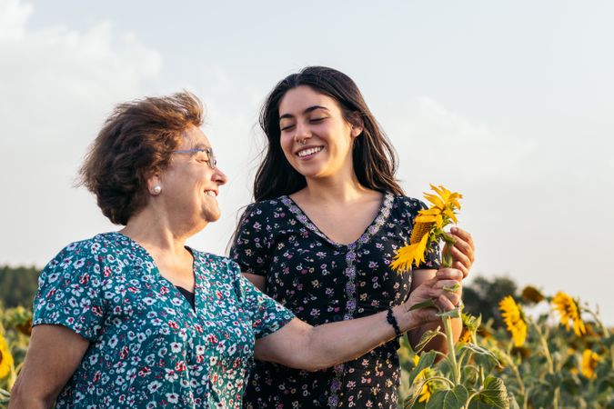 Taking advantage of life Grandmother and granddaughter in a field of sunflowers.