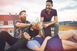 Group of friends lounging an relaxing on a rooftop toasting beers