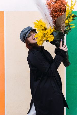 Woman with flowers smiling against colorful wall