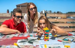 Concentrated woman pushing game piece next to her friends in a rooftop party