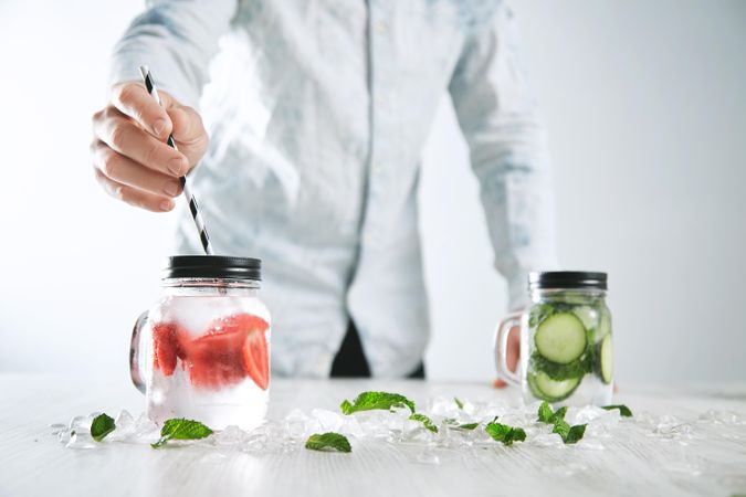 Man putting straw into mason jar of infused water