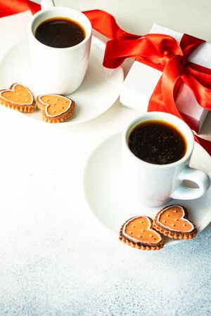 Two coffees on counter with iced cookies and heart candles