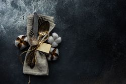 Top view of table setting on concrete background with decorative cotton and feathers on napkin