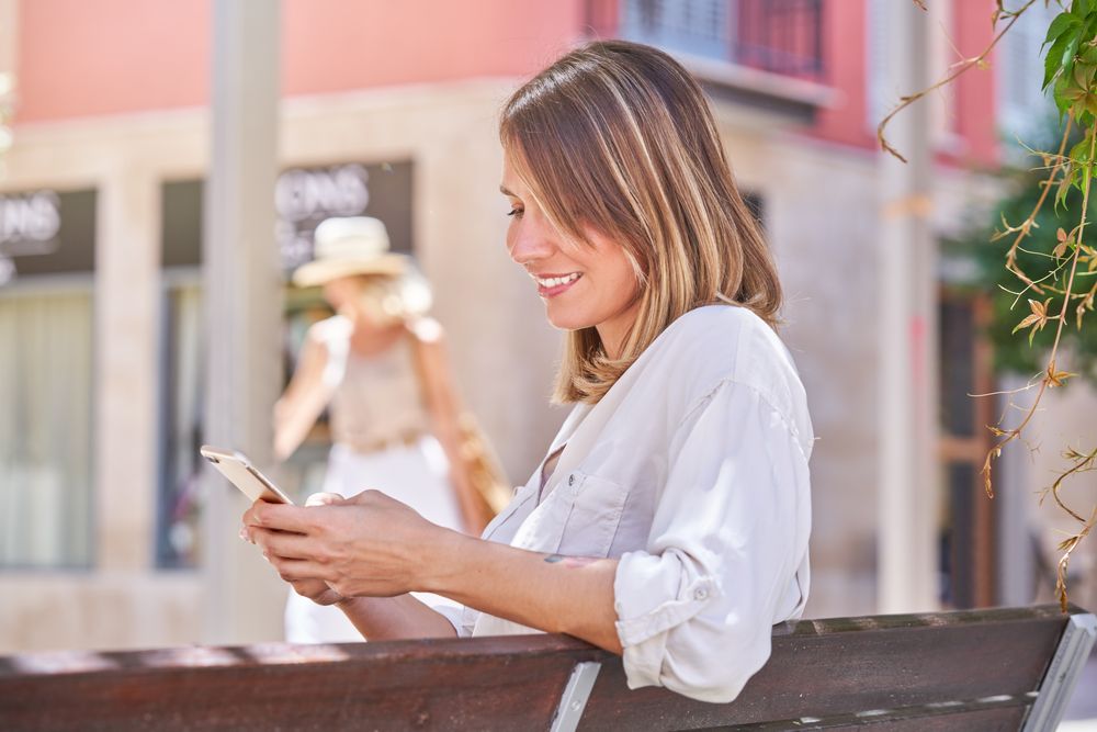 Positive female browsing phone on street