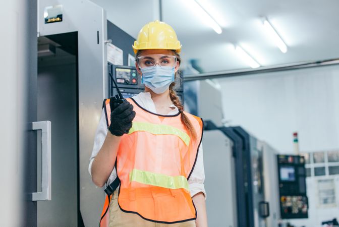 Portrait of female manager industrial engineer in PPE gear and radio phone
