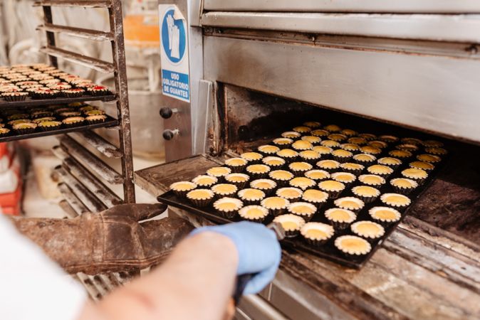 Bald baker checking pastry inside oven