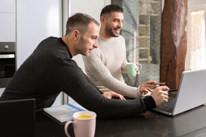 Two men at home with coffee working on kitchen counter