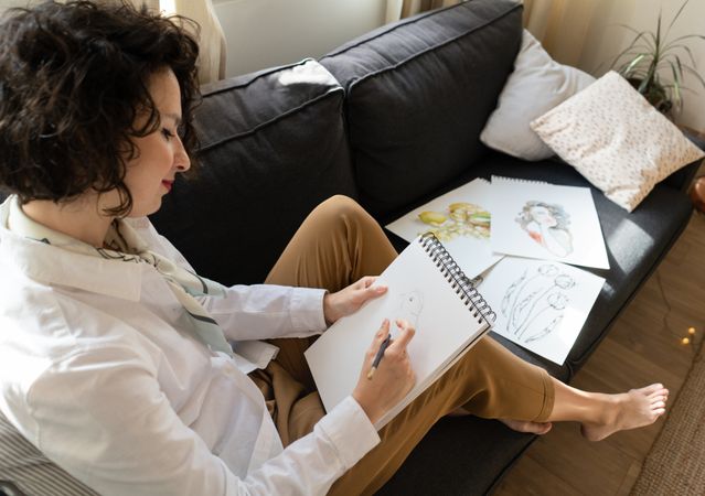 Woman writing on paper on sofa in room