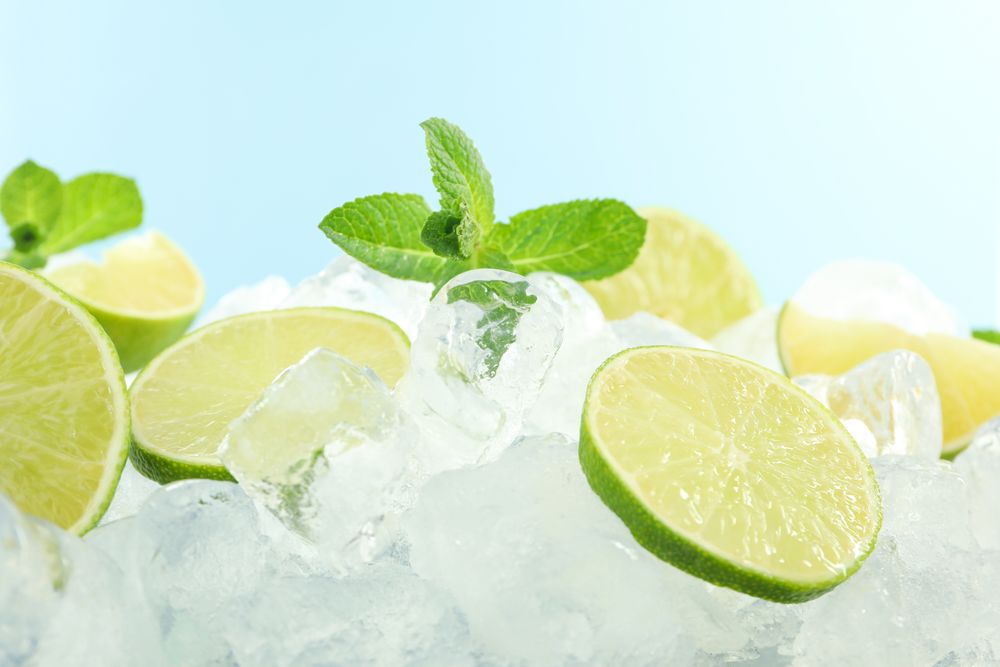 Pile of ice with lime halves and mint in blue room