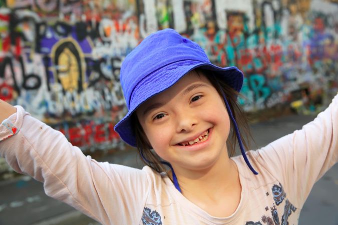 Cute smiling little girl with  Down syndrome with graffiti wall behind