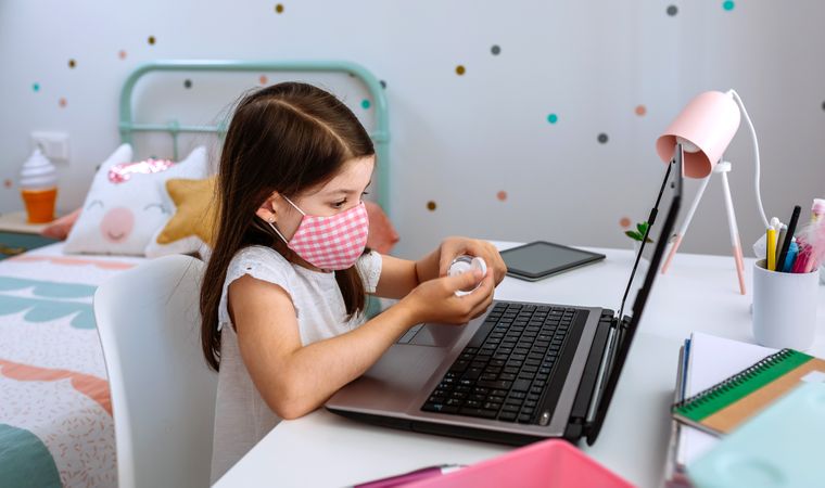 Girl applying hand sanitizer while studying with laptop