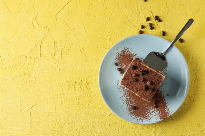 Plate with delicious tiramisu on yellow background. Tasty dessert