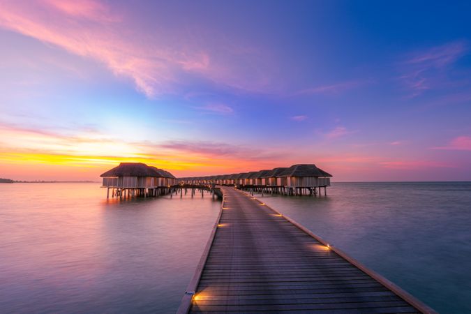 Walkway leading to overwater bungalows at sunset