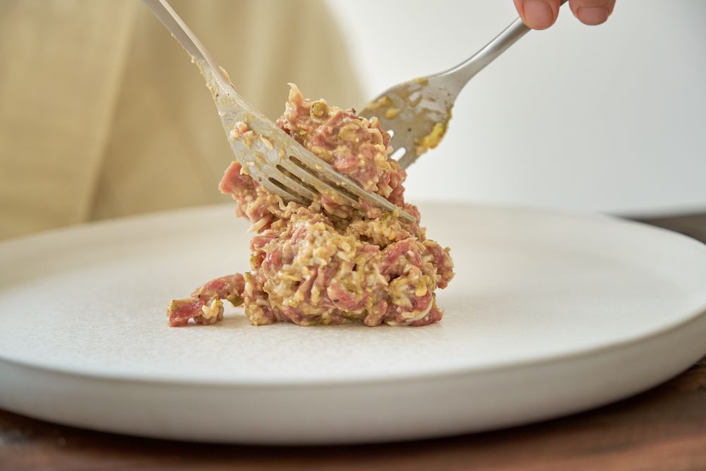 Anonymous person serving appetizing steak tartare on white plate