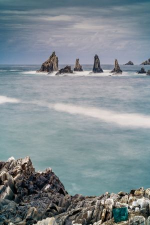 Rocky peaks protrude from water in cloudy day