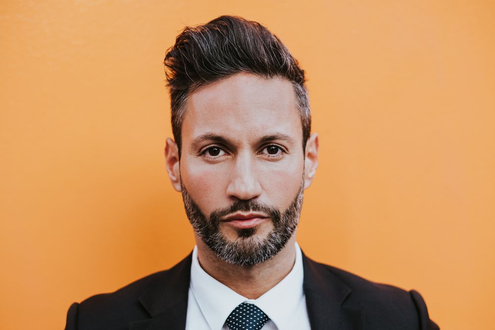 Adult stylish man in costume near orange wall