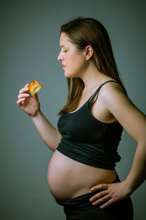 Pregnant women showing her belly and ready to eat cake