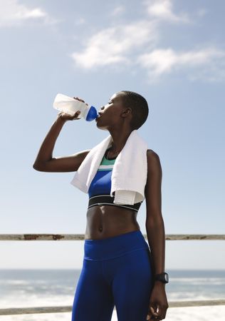 Fit woman drinking water after workout session