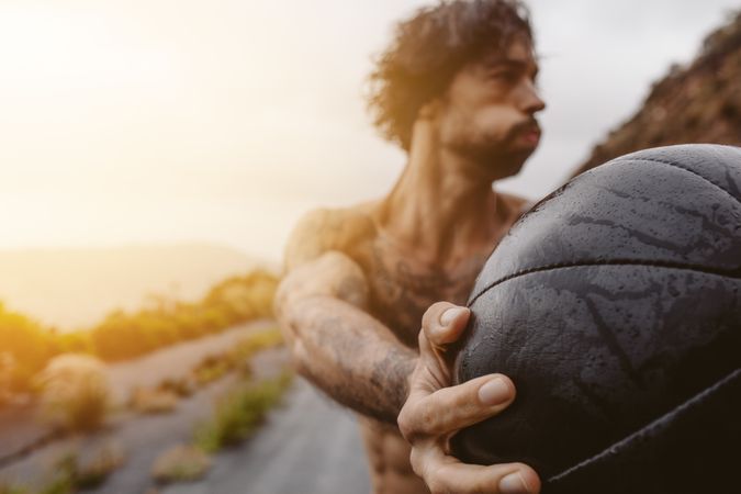 Sportsman exercising with medicine ball outdoors on a rainy day
