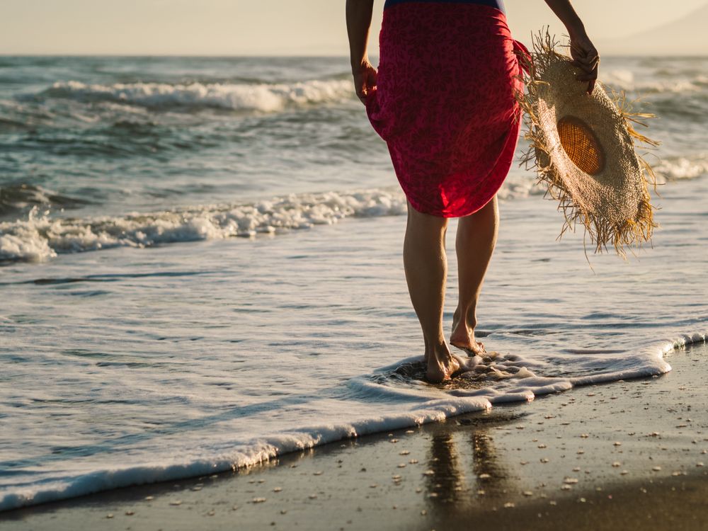 Woman with pink pareo on sandy beach