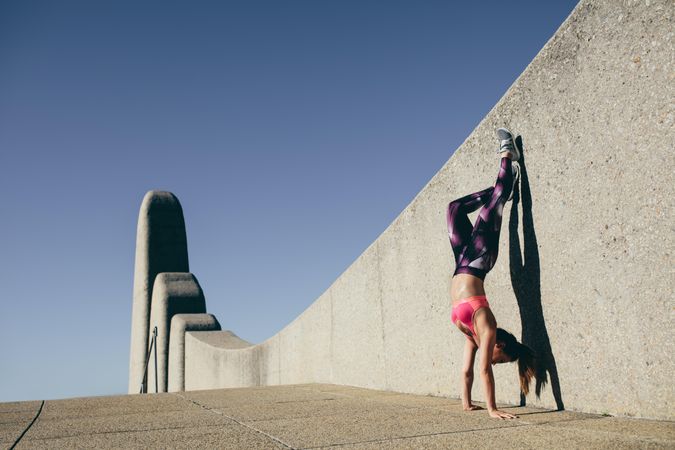 Physically fit woman doing hand stand outdoors