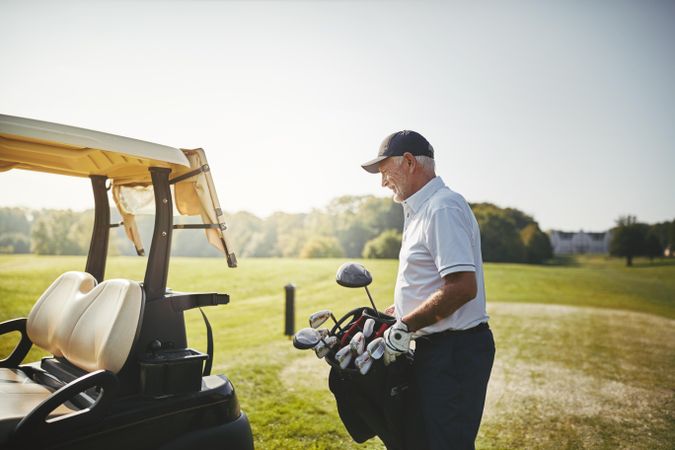 Man loading golf clubs into cart