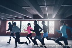 Group of sporty people running together next to a barred window 0Wz8Pb