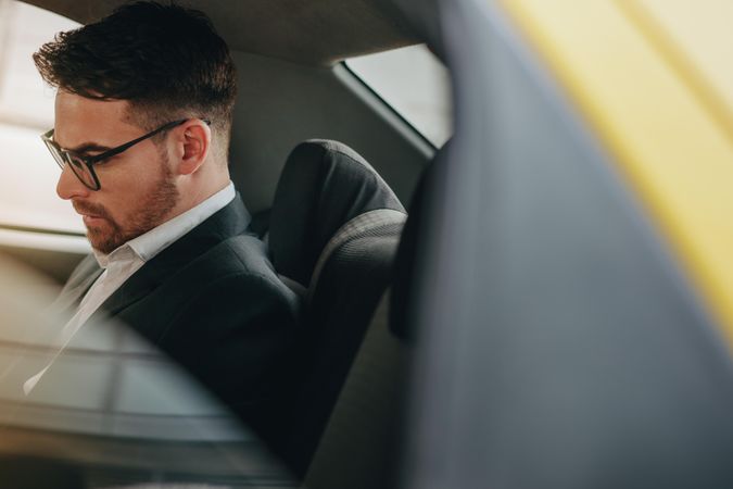 Side view of a businessman sitting in car looking busy