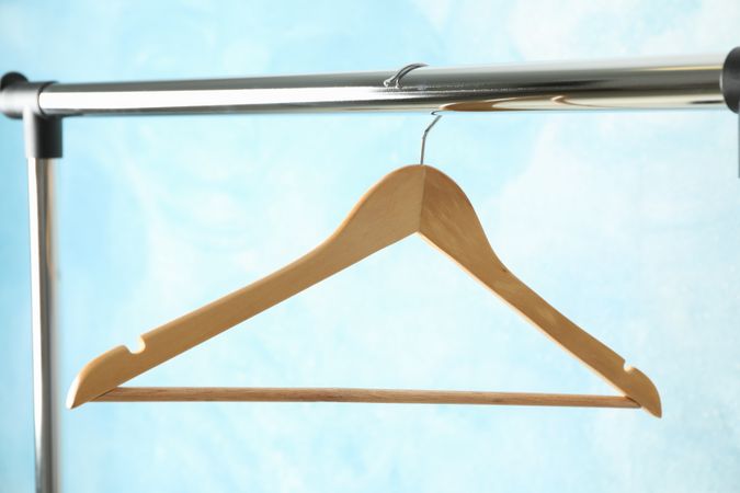 Hanger on rod against blue background, copy space