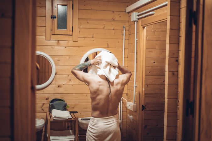 Man getting out of the shower and drying his hair with the towel
