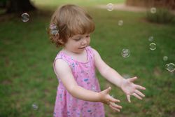 Joyful girl playing with colorful bubbles in grass