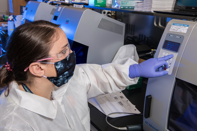 Female scientist working in a laboratory wearing a facemask and goggles