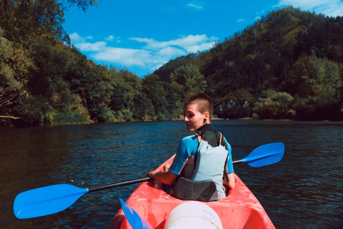Female kayaking with paddle in raised hands