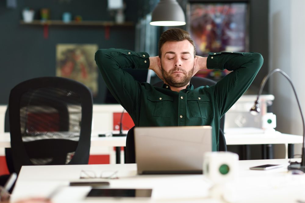 Young male relaxing between studying with laptop computer in modern office