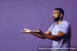 Side view of male in purple studio with hands gesturing at copy space 0W3AO0