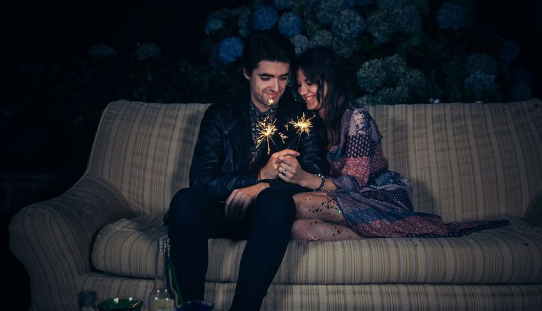 Happy couple in love holding sparklers on a sofa