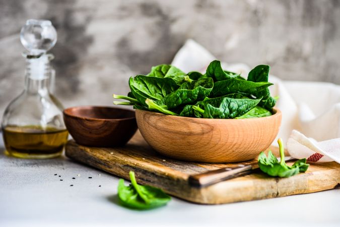 Side view of wooden bowl of fresh spinach leaves on kitchen counter