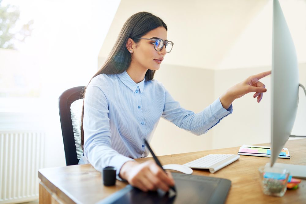 Woman pointing at monitor on her desk while using stylus